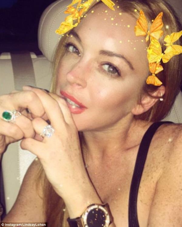 A selfie picture of Lindsay Lohan featuring butterflies on her hair along with an emerald engagement ring