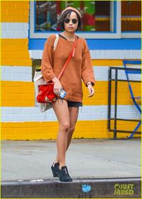 Zoe Kravitz walking in shorts and an orange top