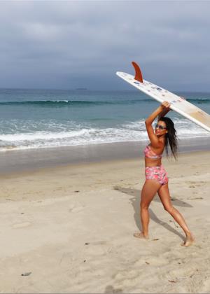 Shay Mitchell at the beach with a surfboard