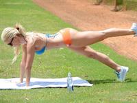Ana Braga in a bikini stretching in a park