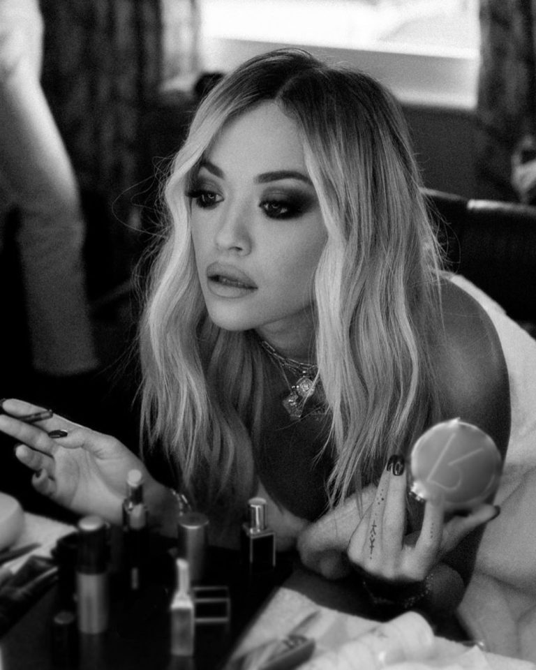 Rita Ora nude in just a robe backstage showing some nice cleavage.


