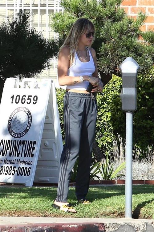 Miley Cyrus Pictures Miley Cyrus braless boobs in a slightly see through white top showing off her tits seen by paparazzi.