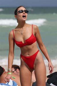 Olivia Culpo sexy ass in a red bikini also showing nice cleavage with her big tits seen on the beach with other models by paparazzi in Miami.