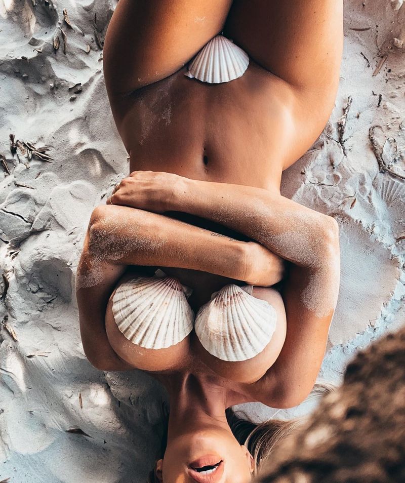 Rosanna Arkle Pictures Rosanna Arkle nude at the beach covering her naked boobs and pussy with shells while laying on the sand.