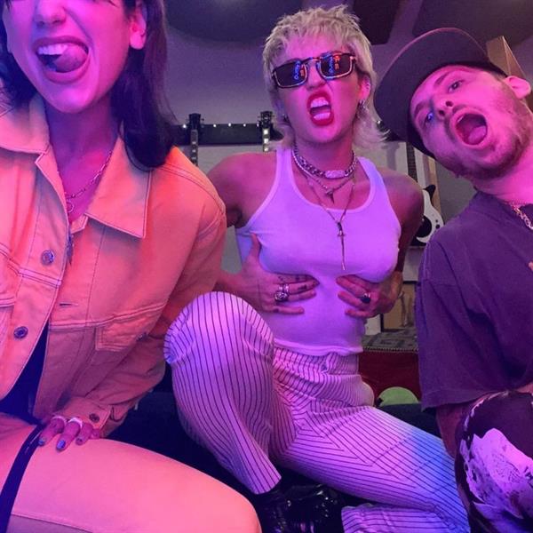 Miley Cyrus braless boobs in a see through white tank top showing off her tits while teasing a collab with Dua Lipa.