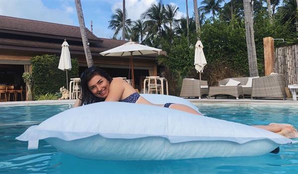 Jess Dardo in a bikini, posing while floating in a pool.